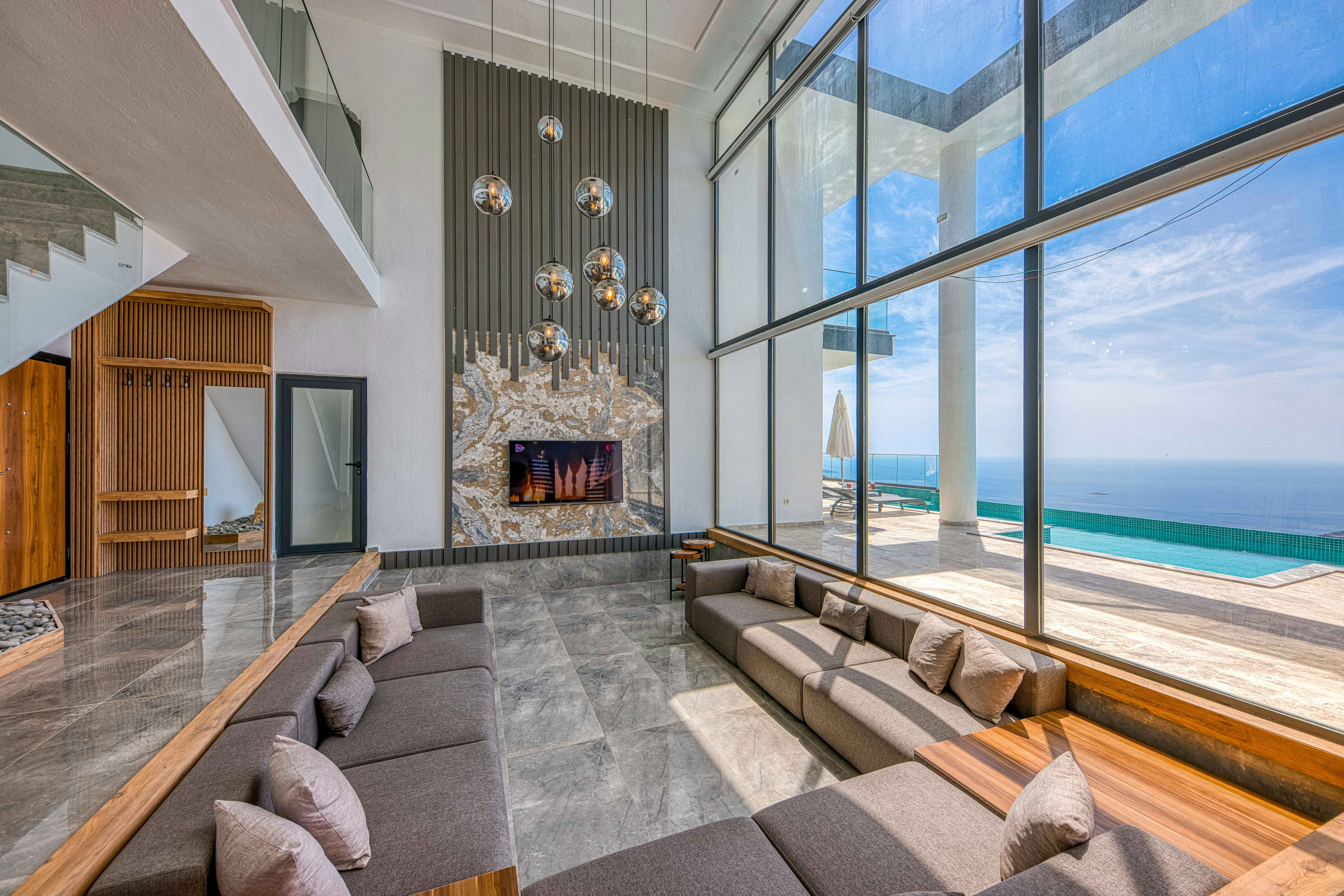 Luxury oceanfront villa with double-height ceilings, floor-to-ceiling windows, and spectacular ocean views with infinity pool